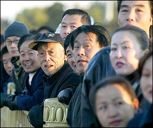 A crowd of onlookers gather to watch in Tiananmen Square as delegates arrive for the opening session of the 16th Communist Party Congress