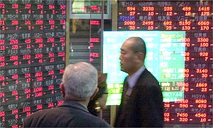 Japanese businessmen glance at Fridays stock prices outside a brokerage house in Tokyo 
