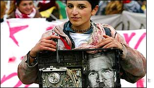 A protester carries a mock-up time bomb with a picture of George W Bush