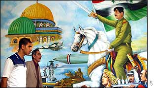 Iraqi men walk past a painting of Saddam Hussein in Baghdad