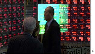 Men look at a stock board in Tokyo