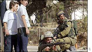 An Israeli soldier trains his gun on a Palestinian neighbourhood in Hebron