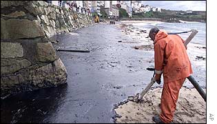 Worker uses special vacuum to clean oil from the beach at Malpica, northern Spain