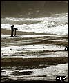 A cameraman films on an oil covered beach