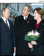 Russian President Vladimir Putin hands flowers to US First Lady Laura Bush as US President George W Bush looks on