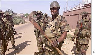 Soldiers look at a weapon used during the riots in Kaduna