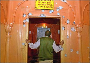 An official inspects bullet holes at the Raghunath Temple following Sunday's attack