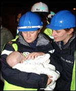 Two armed forces firefighters cradle a baby rescued from flats in Southampton