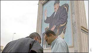 Men beneath a portrait of Saddam Hussein in Baghdad