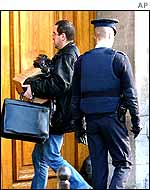 Plainclothes policeman carrying a bundle of documents