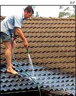 Man hoses leaves from roof to help prevent combustion
