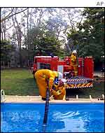 Firemen pump water from a swimming pool at Glenorie