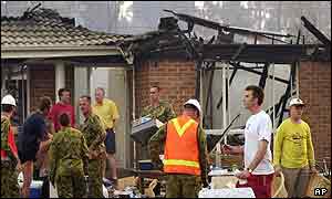 Army staff help move belongings after house caught fire in Wattle Grove, sparked by a forest fire 