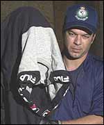 An Australian policeman leads a shrouded suspect away