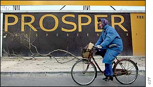 Woman in Beijing cycles past a poster saying 