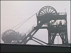 Coal mine pithead silhouetted against grey sky