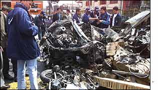 Explosives experts examine the wreck of a car bomb that went off on Monday 