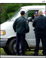 Law enforcement officers perform a spot check of a white van