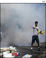 An opposition demonstrator waves a flag in Caracas amid tear gas