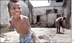 An East Timorese boy smiles as he helps to clean up an East Timorese-own shop burnt out during riots in Dili, East Timor, 7 Dec 2002. 