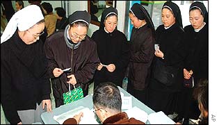 South Korean nuns have their IDs checked by Election Commission workers at a polling station in Busan