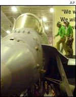 Mechanics walk on the wing of a F/A-18 Hornet on board a US aircraft carrier