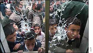 Palestinians look from the outside at bullet holes in the window to the guard position at a hospital in the West Bank city of Ramallah 