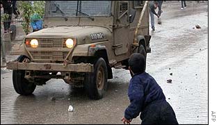 Palestinians attack an Israeli army jeep with stones in the West Bank town of Qalqiliya on Thursday