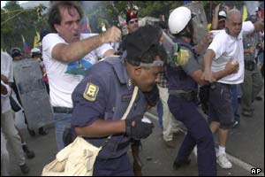 An opposition protester, left, hits a police officer who was firing tear gas, during clashes near Fuerte Tiuna military base in Caracas