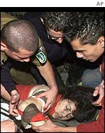 Rescue workers and bystanders attend to an injured woman