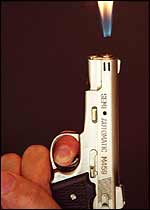 A cigarette lighter in the form of a silver gun 
