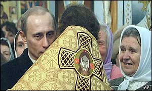 Russian President Vladimir Putin is embraced by an Orthodox priest at a Christmas service