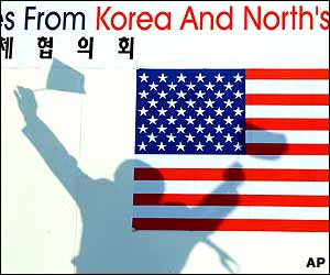 A banner is shadowed by a South Korean citizen group leader waving the flags of the US and South Korea 