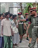 A Sri Lankan military policeman directs captured child Tamil Tiger guerrillas