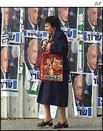 A woman walks in front of election campaign posters