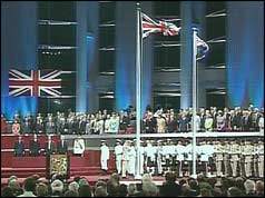 Dignitaries sitting on platform, flags flying in front