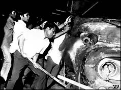 Men topple a smoldering fire truck over during the violence in Bangkok