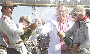 Alinghi crew members spray champagne to celebrate their win