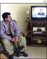 Kurdish fighter watches Saddam Hussein speech on TV