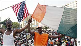 Men wave the US and Ivorian flags outside the US embassy 