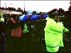 Rescue workers stretcher away an injured passenger