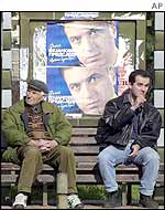 Montenegrins sit in front of election posters