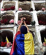 Nogal mourner lays flowers in coffin wall at Bogota cemetery