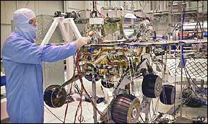 Engineer stands next to a nearly fully-assembled Mars Exploration rover 