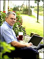 Man having a pint while using a laptop