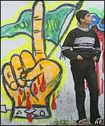 A Palestinian youth next to a Hamas graffiti in Gaza