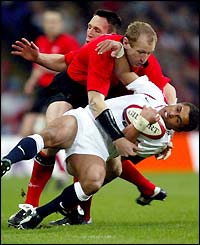 Wales' Gareth Thomas floors England's Jason Robinson as the match starts at a frantic pace