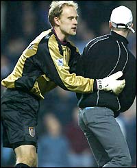 Aston Villa goalkeeper Peter Enckelman restrains a fan who runs onto the pitch from the Holte end
