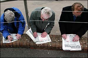 Three betting enthusiasts mark their cards prior to the start of the first day's racing at the Festival