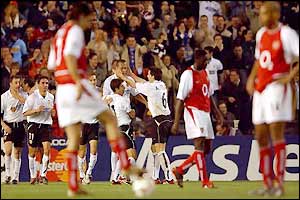 The Arsenal players stand dejected as Valencia celebrate their goal